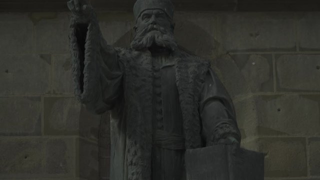 Front View Of The Statue Of Johannes Honterus Pointing Outside The Gothic Black Church In Brasov, Romania - Tilt Up Close Up Shot