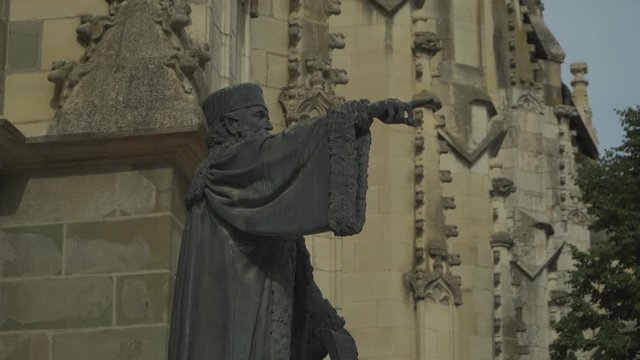 Side View Of The Statue Of Johannes Honterus Outside The Black Church In Brasov, Romania On A Sunny Day With - Tilt Up Shot