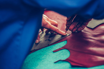 Shoemaker man measuring and cutting leather in a workshop