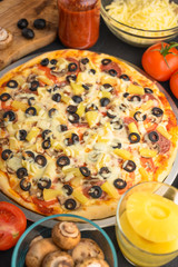 Italian pizza with ingredients on a dark background. Vertical photo.