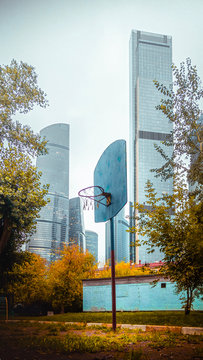 Beautiful view to Moscow City Business Center through colorful autumn trees and basketball hoop in the park on another side of the river. 