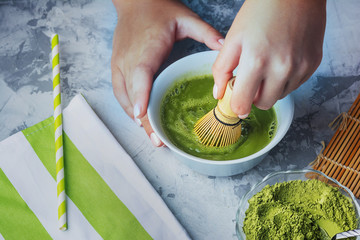 The process of making green tea matcha. Girl stirs a green drink with a bamboo whisk.