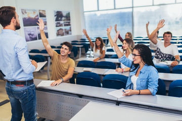 Group of students raising hands in class on lecture