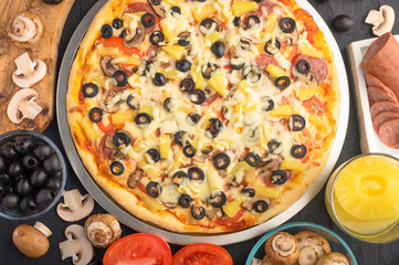 Pizza on a black background with ingredients, tomatoes, salami, mushrooms, sauce and mazzarella...