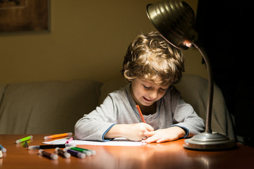 Child drawing illuminated by the light of a lamp.