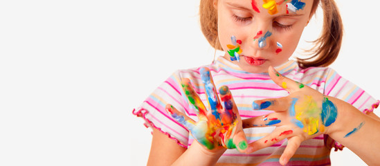 Cheerful young girl showing her hands and face painted in bright colors. Art,  creativity and childhood concept.