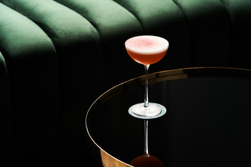 Classic cocktail glass on glass table in night club restaurant, close-up