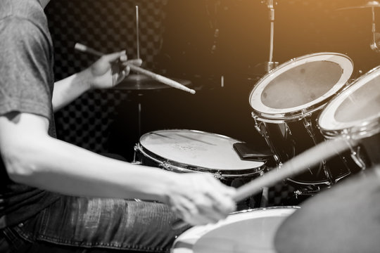 Young musicians wear t-shirts, jeans, and play the drum set and cymbals with wooden drumsticks in music room , the concept of musical instrument.