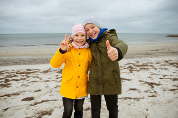 Portrait of two happy teenagers staing on coast of Baltic sea at windy rainy weather