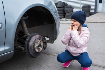 A child looks at a broken car. Repair service.