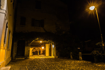 Stone passage under an old building in the city center at night Treviso Italy
