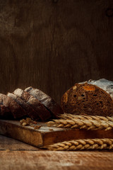Freshly baked wheat bread, homemade cakes, still life with bread, crisp loaf of bread, still life on a rustic background, top view, rustic bread, roll, loaf.