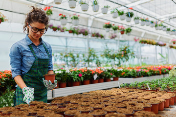 Young woman working in beautiful colorful flower garden greenhouse - Powered by Adobe