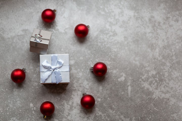 White gift box with white ribbon bow and vinous christmas balls around, isolated on gray background