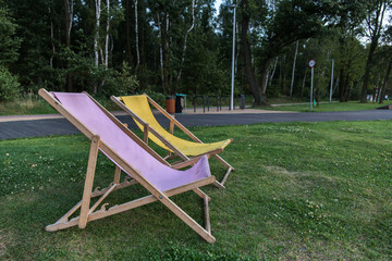 Two empty sun beds on the grass in a park