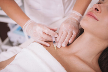 Fototapeta na wymiar Cropped shot of a woman getting hyaluronic acid injections in her chest skin. Female client getting skin tightening treatment at beauty clinic