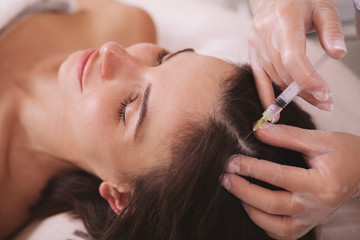 Fototapeta premium CLose up of a woman getting vitamin injections in her scalp. Female client receiving hairloss treatment by professional dermatologist
