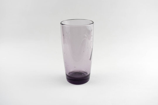 Glass of dark glass with drops of water on a white background.