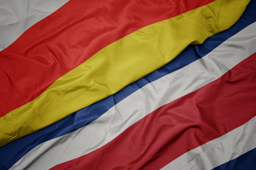 waving colorful flag of costa rica and national flag of south ossetia.