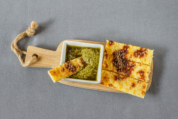 Cheesy keto sticks with sesame and pesto sauce on wooden background