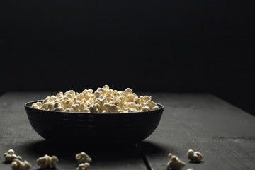 popcorn on black background and wooden board
