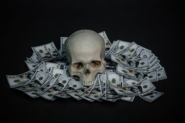 A human skull lies in the dark on money.