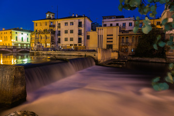 Fototapeta na wymiar View on waterfall and a dam on Sile river with beautiful blue sky at night Treviso Italy
