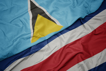 waving colorful flag of costa rica and national flag of saint lucia.
