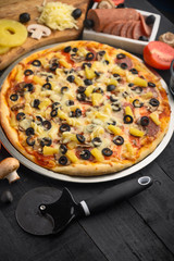 Pizza with ingredients, tomatoes, salami, mushrooms, mazzarella sauce and cheese and pizza knife. Italian pizza, culinary recipes concept, menu, restaurant, gourmet kitchen. Vertical frame