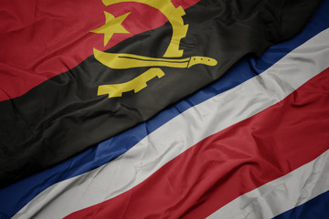 waving colorful flag of costa rica and national flag of angola.
