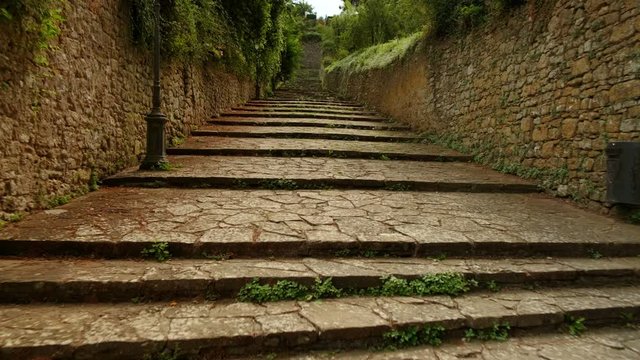 Walking the beautiful steps of Porta di Docciola with small shrubs of vegetation towards Volterra a walled town in Tuscany, Italy