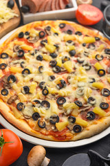 Pizza with ingredients, tomatoes, salami, mushrooms, mazzarella sauce and cheese and pizza knife. Italian pizza, culinary recipes concept, menu, restaurant, gourmet kitchen. Vertical frame