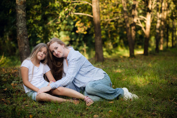 Naklejka na ściany i meble Mother and daughter lying on a grass outdoors and smiling
