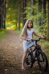 Fototapeta na wymiar Little girl having fun on bike in the forest in autumn season