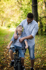 Father teaching his son to ride a bike in a autumn park