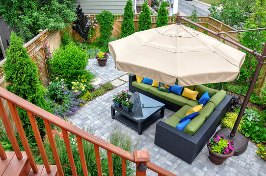 A beautiful small, urban backyard garden featuring a tumbled paver patio, flagstone stepping stones, and a variety of trees, shrubs and perennials add colour and year round interest. 