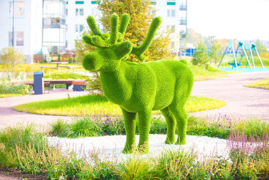 Green artificial topiary in the form of an animal elk in the yard, decoration of playgrounds and local areas.