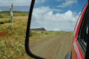 view of the road and the mountain from the rearview mirror of a car