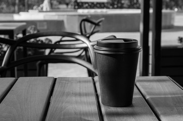 Hot coffee in a paper Cup on a table in a street cafe