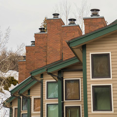 Square Townhomes with white exterior wall and red brick chimneys viewed in winter