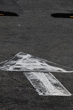 white painted arrow on asphalt showing driving direction