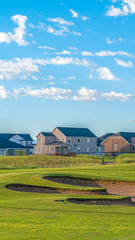 Vertical frame Golf course and houses with distant mountain and blue sky view on a sunny day