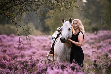 Reiterin schmust mit ihrem Pony in der Heide unter einem Baum