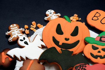 The hand-made eatable gingerbread Halloween pumpkin, ghosts, bat and sceletons on black background