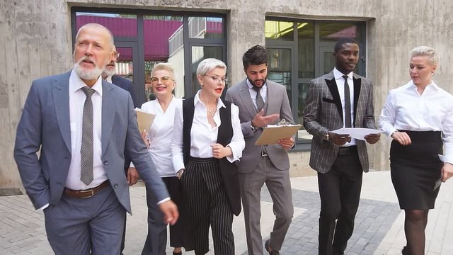 Group of businessmen wear stylish suits move outdoor.