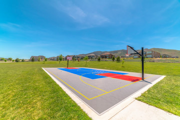 Obraz premium Basketball court at a park against houses and buildings viewed on a sunny day