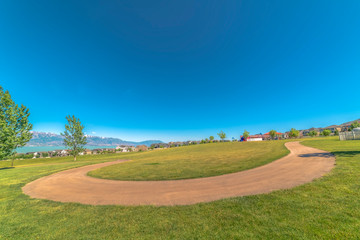 Pathway winding on a vast grassy terrain with lake and snow capped mountain view