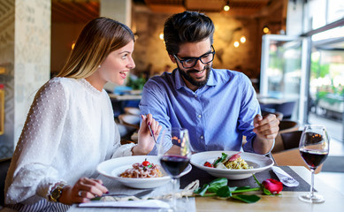 Paste and red wine. Young couple enjoying lunch in the restaurant. Lifestyle, love, relationships, food concept