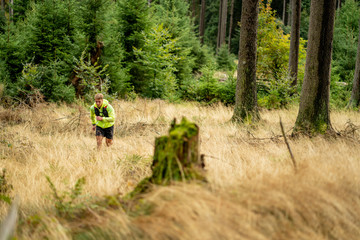 Young athlete runs uphill with a drinking backpack. Trail run in a beautiful autumn forest