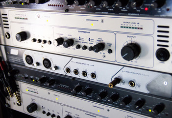 A rack of audio compressors in a recording studio